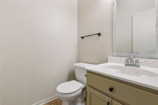 half bath with toilet, vanity, and baseboards