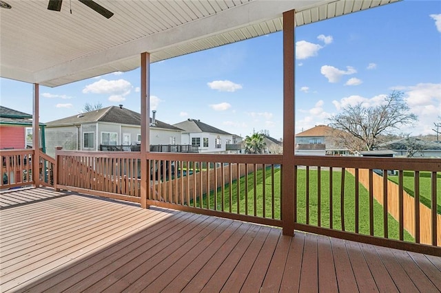 deck with a residential view, a ceiling fan, and a lawn