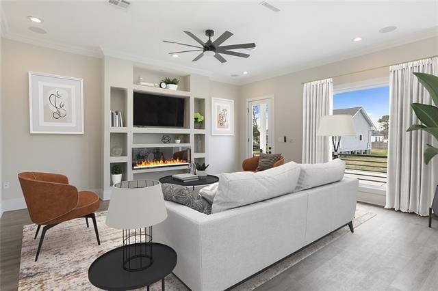 living area featuring light wood-type flooring, a glass covered fireplace, and visible vents