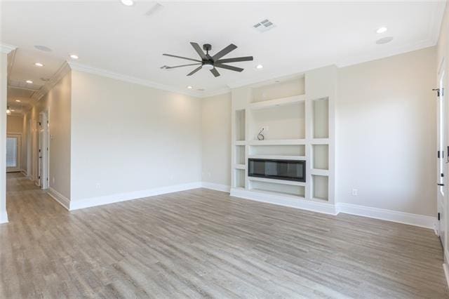 unfurnished living room with light wood finished floors, a glass covered fireplace, visible vents, and built in features