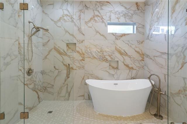 bathroom featuring a freestanding tub and a marble finish shower