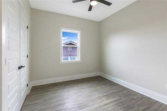 empty room with a ceiling fan, baseboards, and wood finished floors