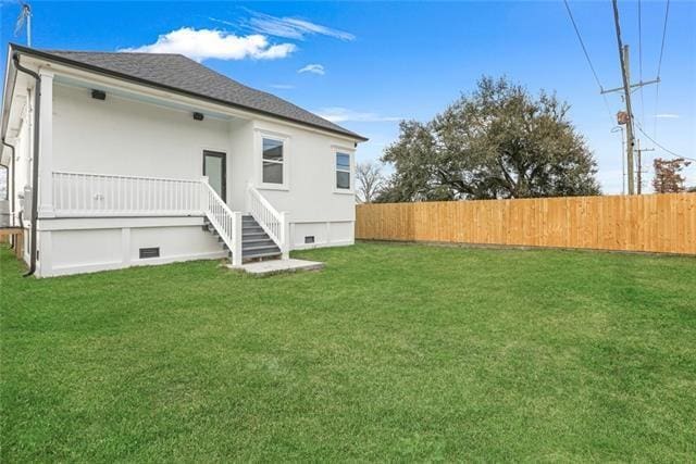 rear view of house featuring a yard, crawl space, and fence