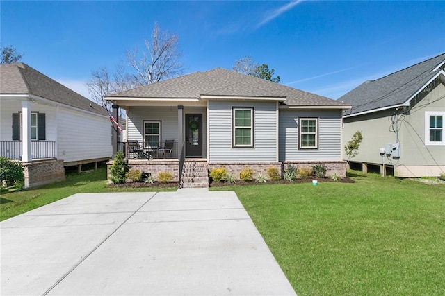 view of front of property with covered porch, a front lawn, roof with shingles, and brick siding