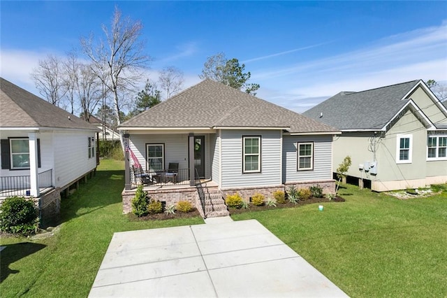 rear view of property with a porch, roof with shingles, and a lawn