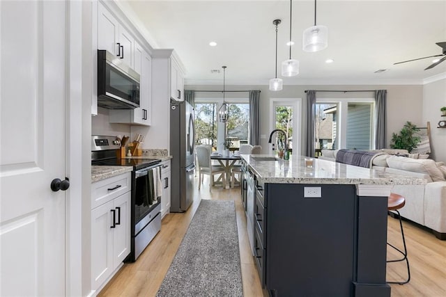 kitchen with appliances with stainless steel finishes, open floor plan, a sink, an island with sink, and a kitchen breakfast bar