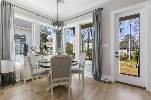 dining area featuring light wood finished floors, visible vents, and an inviting chandelier