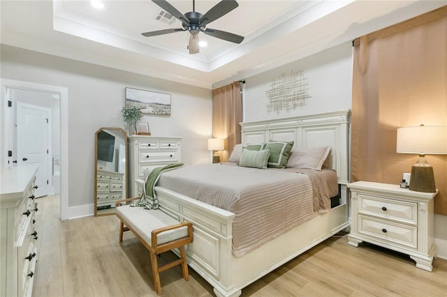 bedroom featuring ornamental molding, light wood-type flooring, a raised ceiling, and visible vents