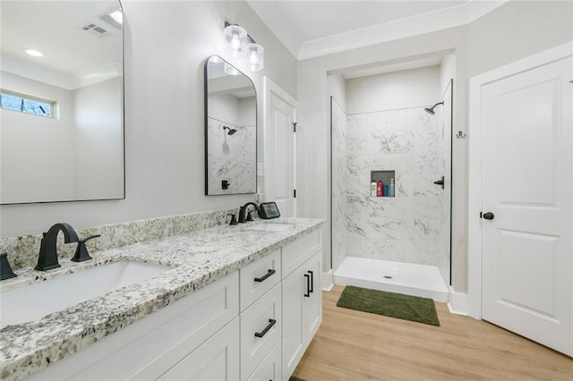 bathroom with double vanity, a sink, a shower stall, and wood finished floors