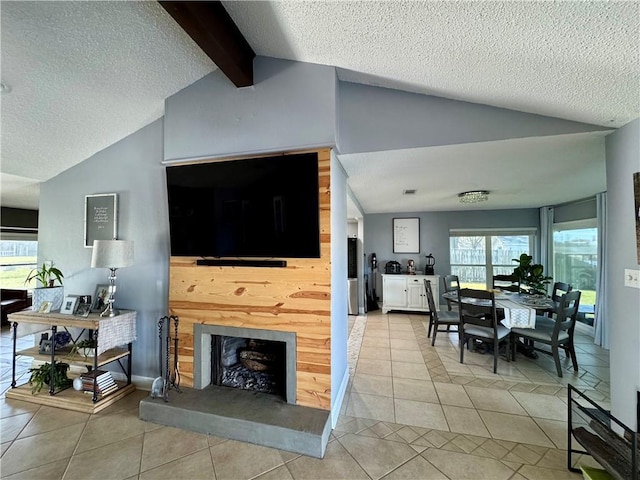 tiled living room with vaulted ceiling with beams, plenty of natural light, a fireplace with raised hearth, and a textured ceiling