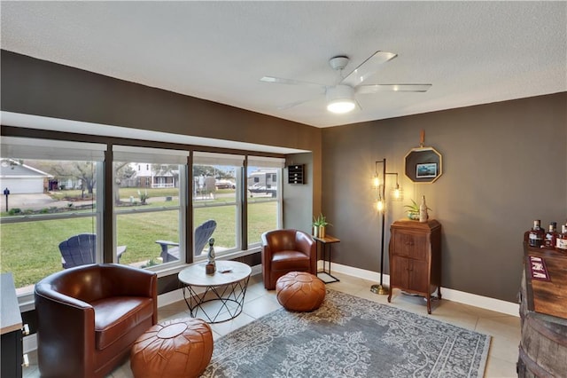 sitting room featuring ceiling fan, baseboards, and light tile patterned floors