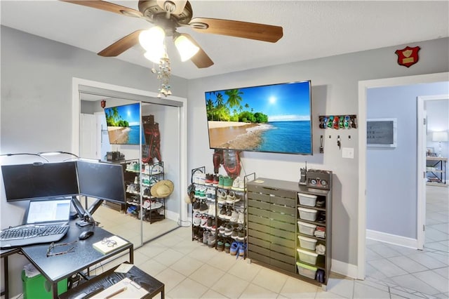 office with light tile patterned floors, a ceiling fan, and baseboards