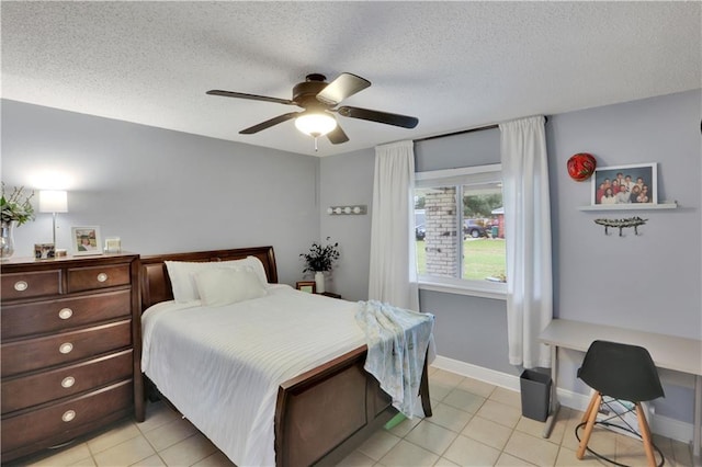 bedroom with light tile patterned floors, ceiling fan, baseboards, and a textured ceiling