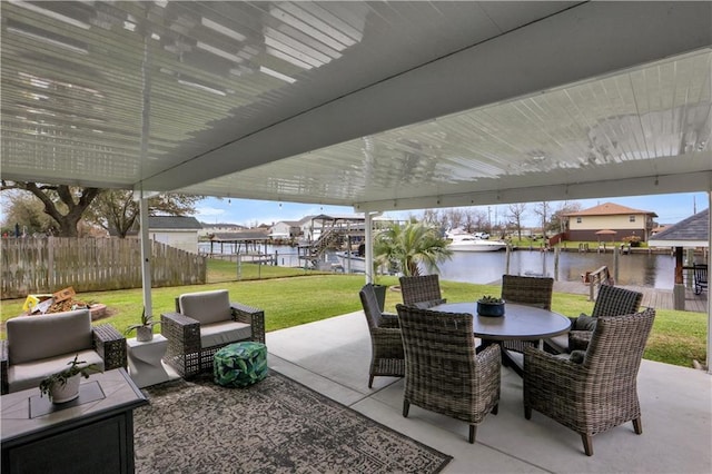 view of patio / terrace with a water view, fence, and outdoor dining area