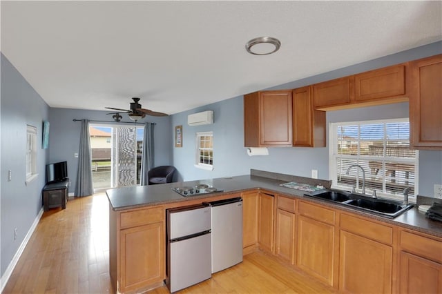 kitchen with dark countertops, freestanding refrigerator, an AC wall unit, a sink, and a peninsula