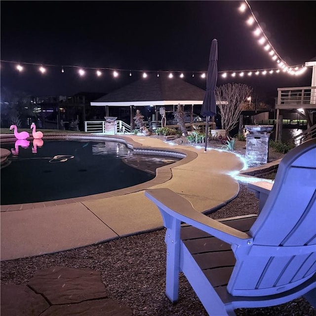 pool at night with a patio area