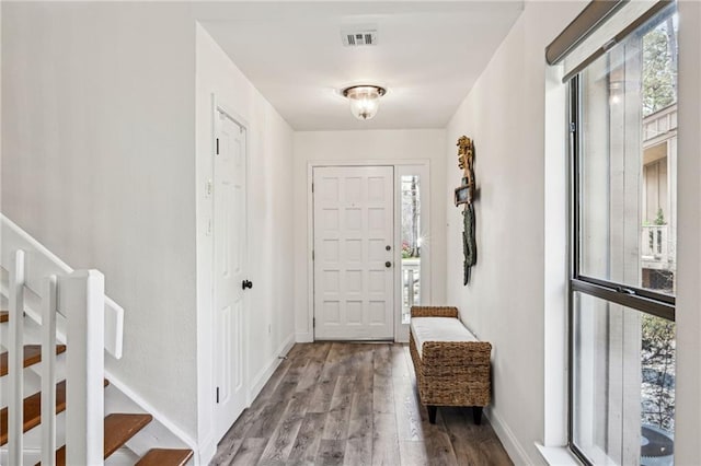 foyer featuring stairway, wood finished floors, visible vents, and a healthy amount of sunlight