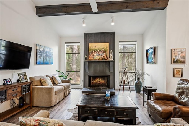 living room featuring lofted ceiling with beams, wood finished floors, and a tile fireplace