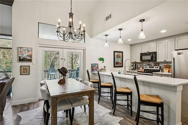 dining room with a notable chandelier, wood finished floors, visible vents, baseboards, and french doors