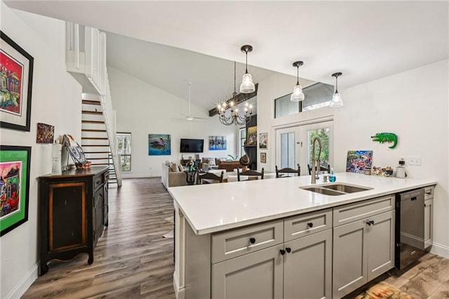 kitchen featuring gray cabinetry, a peninsula, a sink, light countertops, and stainless steel dishwasher