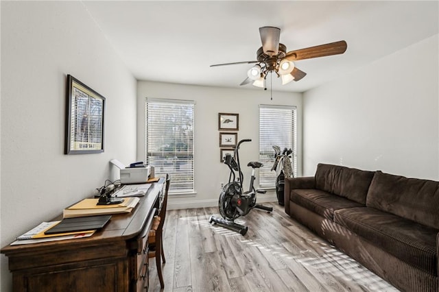 exercise room featuring ceiling fan, light wood-style flooring, and baseboards