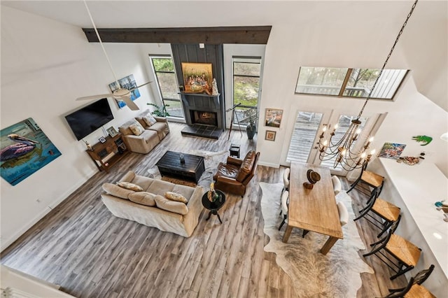 living room with a warm lit fireplace, a notable chandelier, and wood finished floors