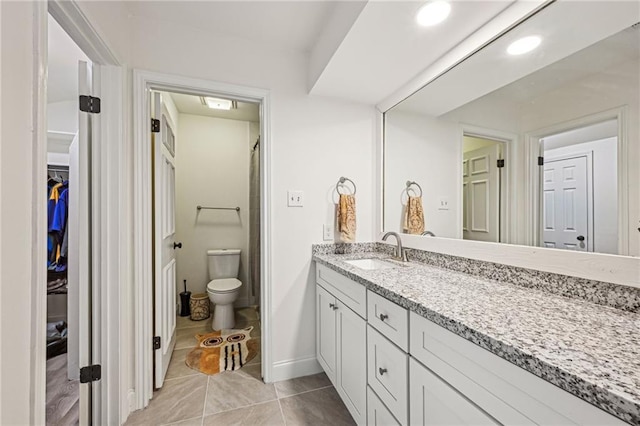 full bath featuring baseboards, toilet, tile patterned floors, a walk in closet, and vanity