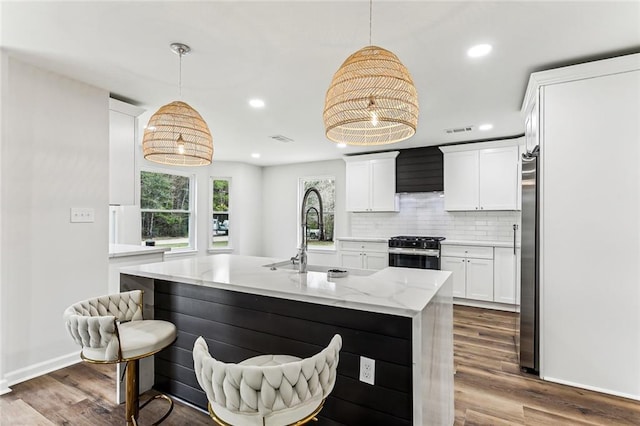 kitchen with appliances with stainless steel finishes, a sink, backsplash, and dark wood-style floors