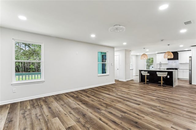 interior space featuring tasteful backsplash, a wealth of natural light, visible vents, open floor plan, and wall chimney exhaust hood