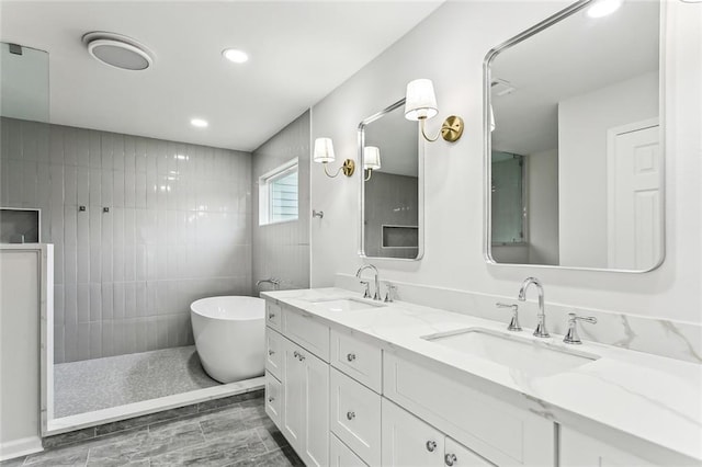 bathroom with a freestanding bath, double vanity, a sink, and recessed lighting