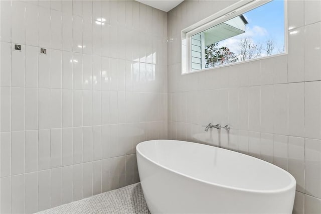 bathroom with a soaking tub and tile walls