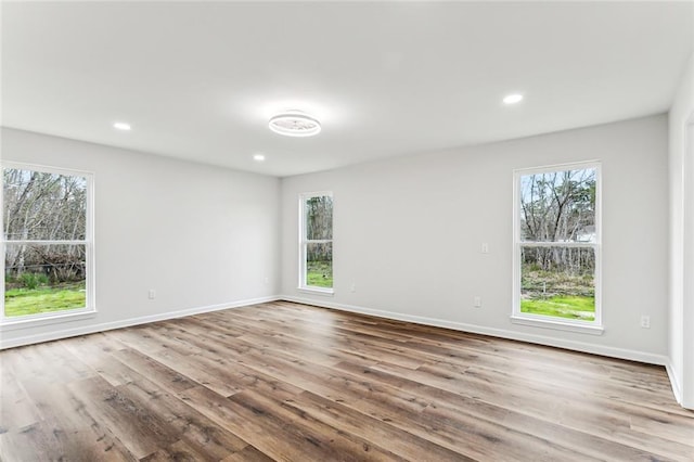 empty room featuring recessed lighting, wood finished floors, and baseboards