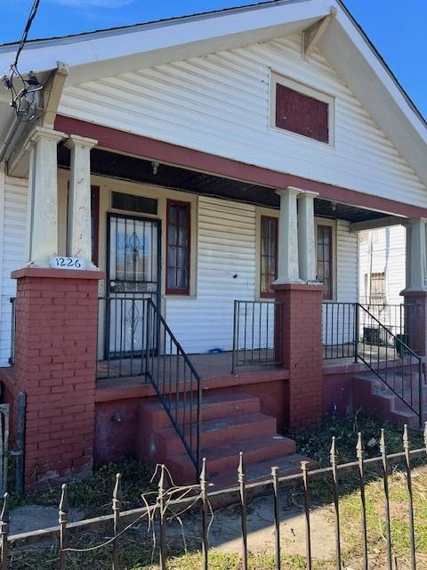 view of front of home featuring a porch and fence