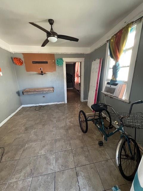 interior space with a ceiling fan, tile patterned flooring, baseboards, and cooling unit