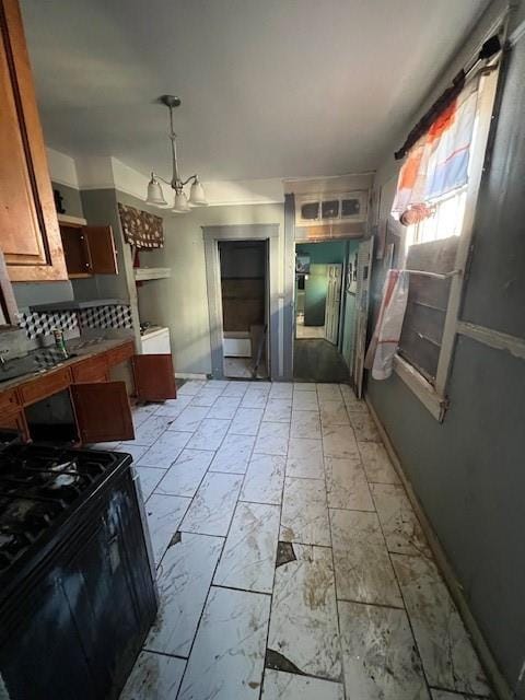 kitchen featuring marble finish floor, black range with gas cooktop, baseboards, and a notable chandelier