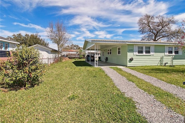 back of property featuring driveway, fence, a carport, and a yard