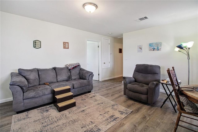 living room with wood finished floors, visible vents, and baseboards