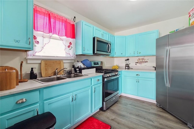 kitchen featuring blue cabinetry, appliances with stainless steel finishes, light countertops, and a sink