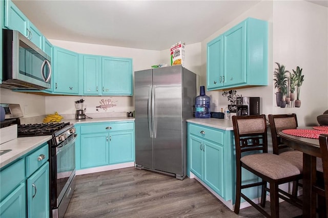 kitchen with light countertops, appliances with stainless steel finishes, dark wood finished floors, and blue cabinets