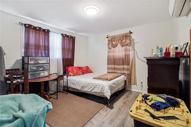 bedroom with an AC wall unit, baseboards, and wood finished floors