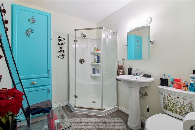 bathroom featuring a stall shower, baseboards, toilet, and wood finished floors