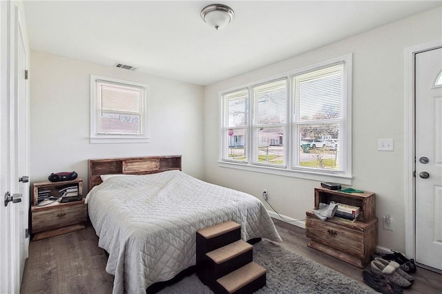 bedroom with baseboards, visible vents, and wood finished floors