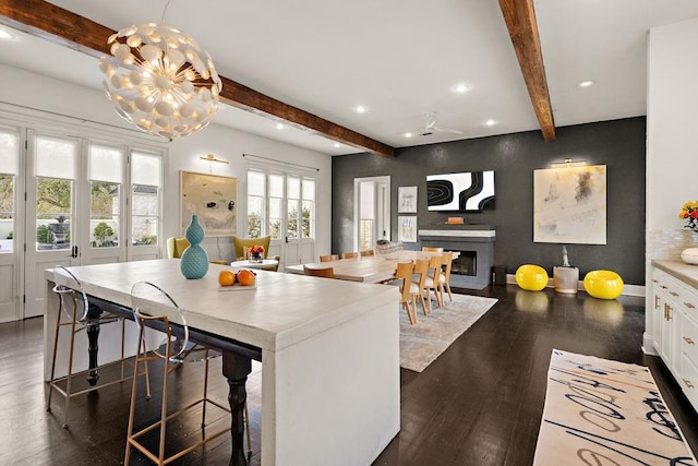 kitchen featuring dark wood finished floors, beam ceiling, recessed lighting, a fireplace, and white cabinetry