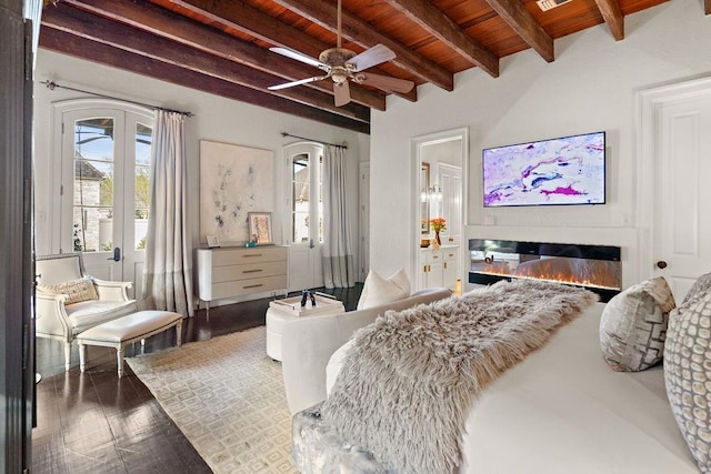 bedroom featuring visible vents, beam ceiling, wood finished floors, a glass covered fireplace, and wood ceiling