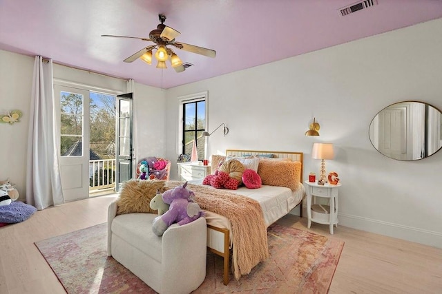 bedroom with visible vents, baseboards, wood finished floors, and access to outside