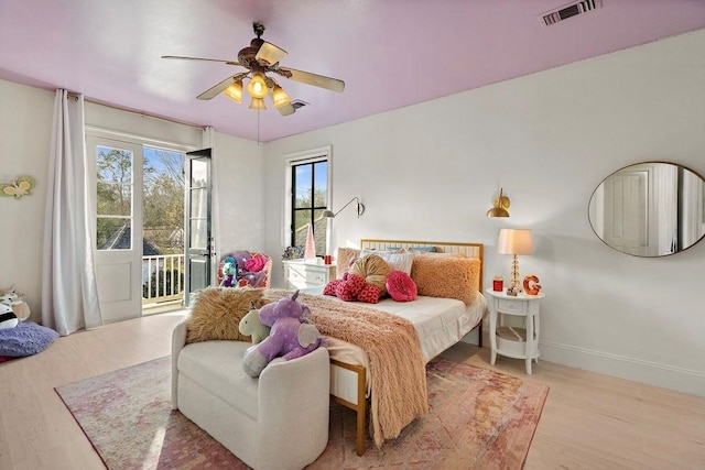 bedroom featuring visible vents, baseboards, a ceiling fan, wood finished floors, and access to outside