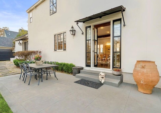 property entrance featuring a patio area, stucco siding, and outdoor dining area