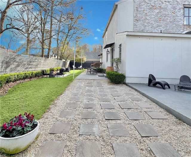 view of property exterior with a yard, a patio area, fence, and stucco siding