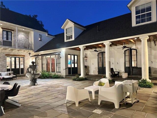 back of house at twilight with outdoor lounge area, stucco siding, french doors, a patio area, and ceiling fan