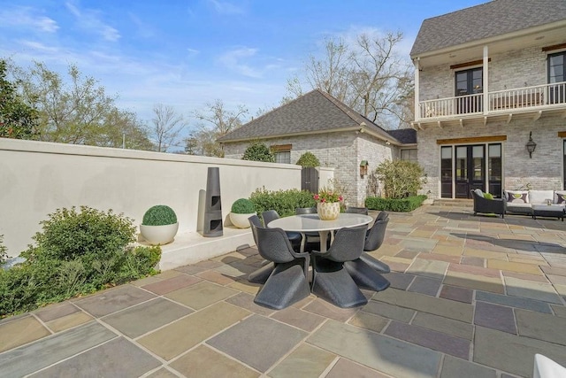 view of patio featuring french doors, outdoor dining area, and a balcony